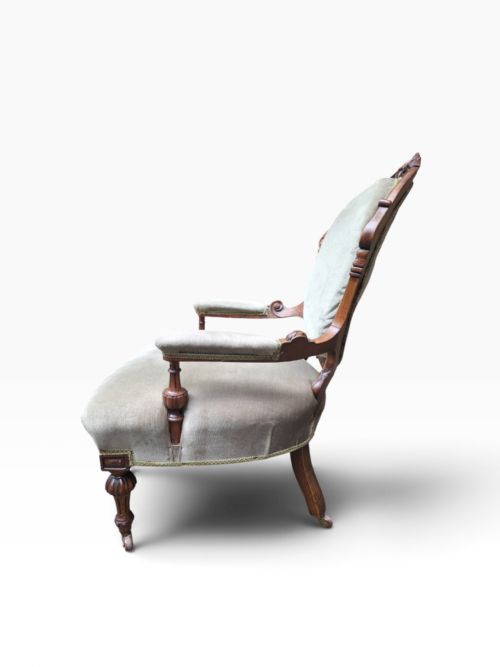 fig 1. A pair of Victorian carved walnut armchairs upholstered in light sage green velvet, featuring one gentlemans armchair with padded arms and one armless ladys chair.
