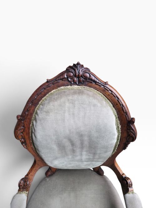 fig 2. A pair of Victorian carved walnut armchairs upholstered in light sage green velvet, featuring one gentlemans armchair with padded arms and one armless ladys chair.