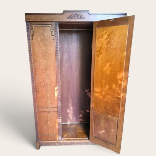 fig 2. An antique 1920s Art Deco oak wardrobe featuring a central mirrored door, geometric inlay detailing, and carved accents.