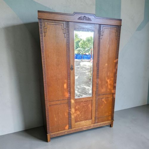 fig 3. An antique 1920s Art Deco oak wardrobe featuring a central mirrored door, geometric inlay detailing, and carved accents.