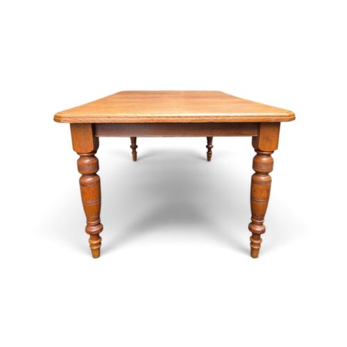 fig 1. A late Victorian oak extending dining table featuring turned legs, clipped rectangular corners, and an integrated metal winding handle mechanism.