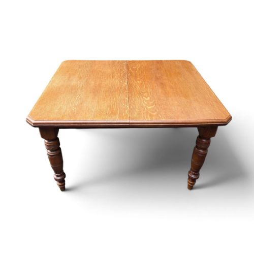 fig 2. A late Victorian oak extending dining table featuring turned legs, clipped rectangular corners, and an integrated metal winding handle mechanism.