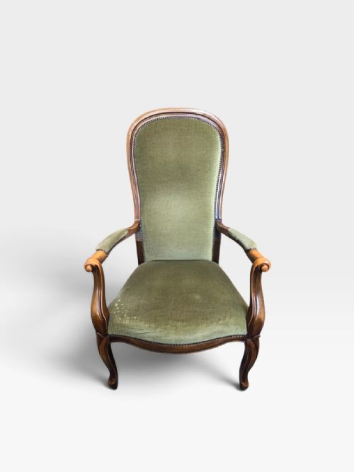 fig 2. An antique Victorian high back armchair featuring a polished timber frame, olive green velvet upholstery, and brass stud trim.