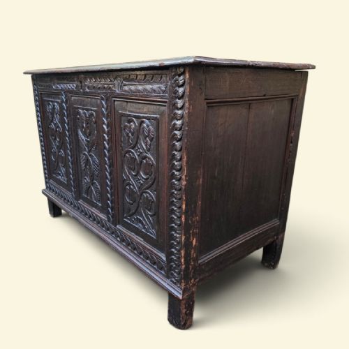 fig 1. A dark Georgian oak coffer featuring three detailed relief-carved front panels with floral motifs and carved stiles on short square feet.