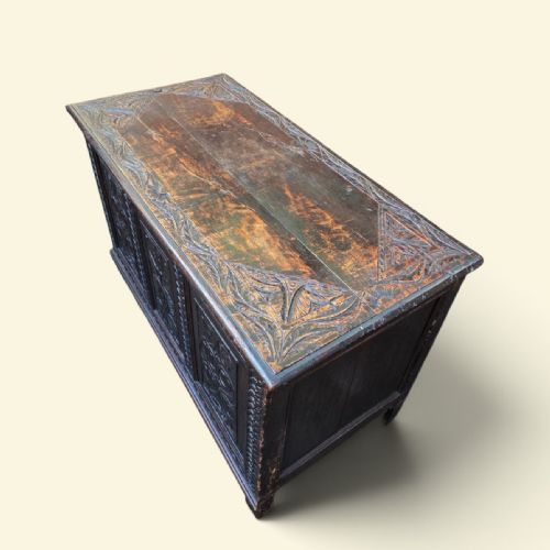 fig 2. A dark Georgian oak coffer featuring three detailed relief-carved front panels with floral motifs and carved stiles on short square feet.