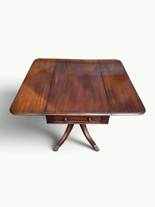 fig 2. A William IV mahogany Pembroke table featuring drop-leaf flaps, a central turned pedestal, and four splayed legs with brass paw feet.