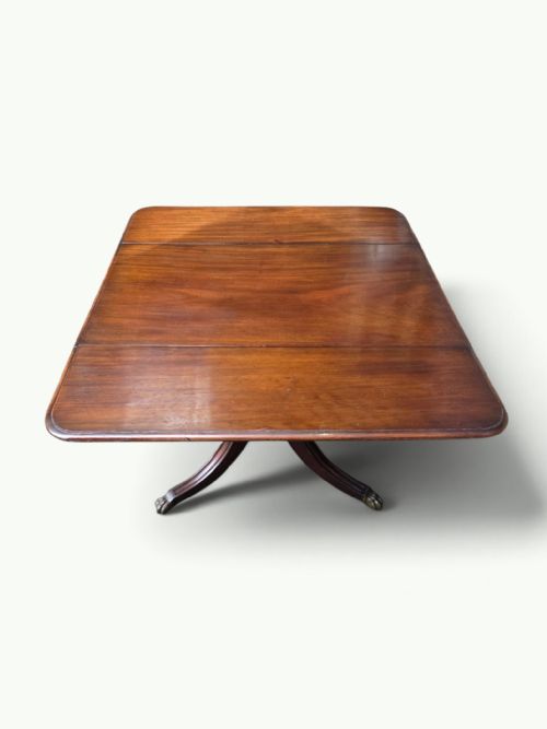 fig 4. A William IV mahogany Pembroke table featuring drop-leaf flaps, a central turned pedestal, and four splayed legs with brass paw feet.