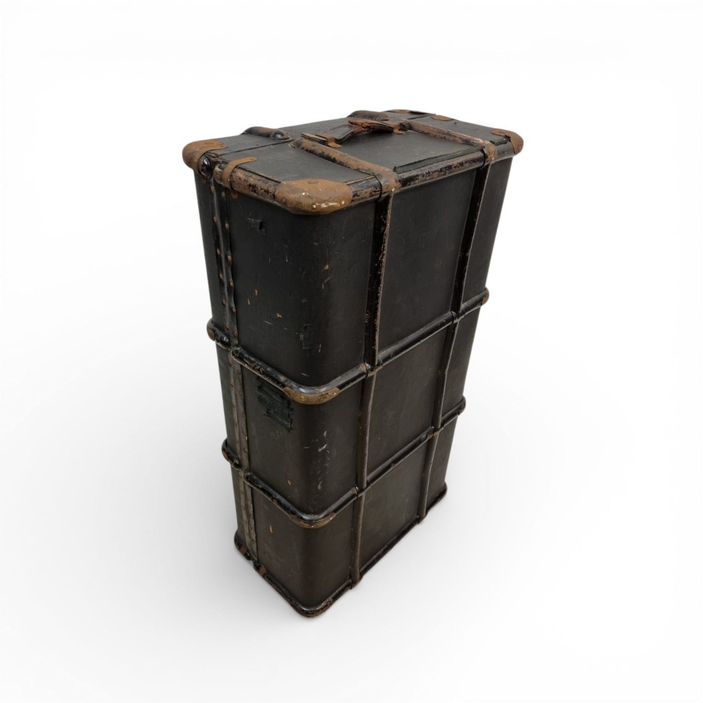 A rectangular black travel trunk featuring dark wooden reinforcement bands, brass latches, and reinforced metal corner caps. View IV