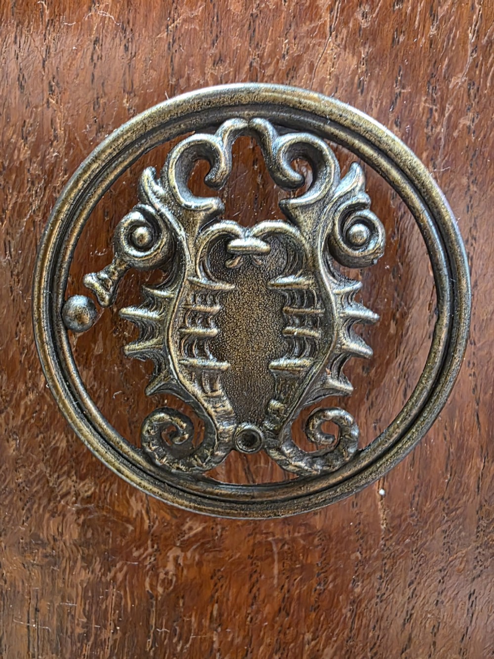 A 1930s Art Deco warm brown wooden wardrobe featuring a single central door with an arched top profile, oval motif carving, and round handle. View IV