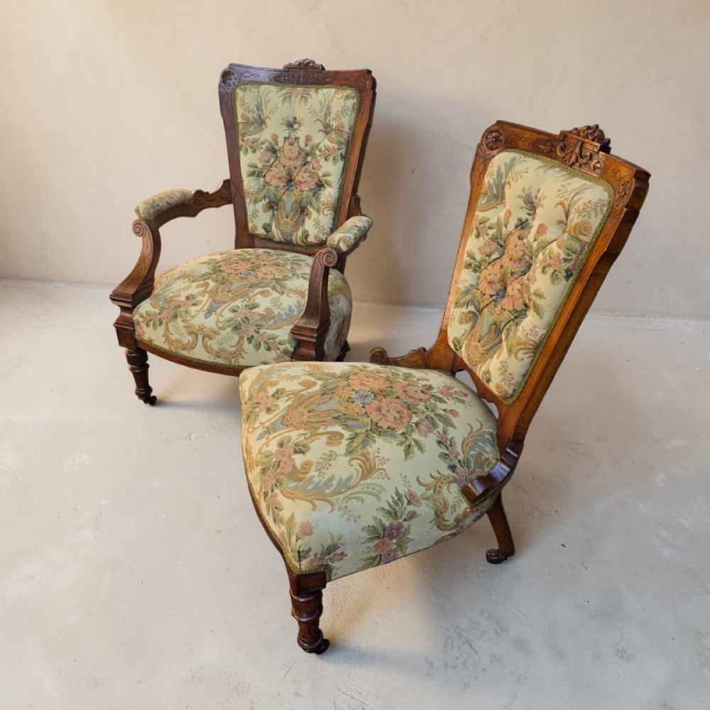 A pair of Victorian carved walnut salon chairs upholstered in green floral tapestry fabric, comprising one armchair and one armless slipper chair.
