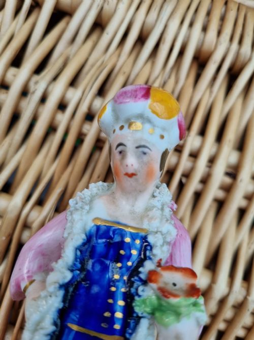 fig 1. A 19th-century Staffordshire earthenware ceramic figurine depicting a figure wearing a turban, pink coat, and cobalt blue tunic with white textured trim.