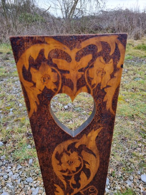 fig 1. A 19th-century Welsh folk art spinning chair with a tall back featuring a heart cut-out, floral pyrography, a hexagonal seat with a carved dragon motif, and four turned legs.