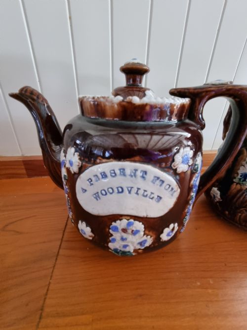 fig 1. A pair of Victorian Measham Bargeware stoneware vessels, including a teapot inscribed A Present From Woodville and a jug inscribed Mrs C Drake 1893, both featuring dark brown treacle glaze and sprigged floral decoration.