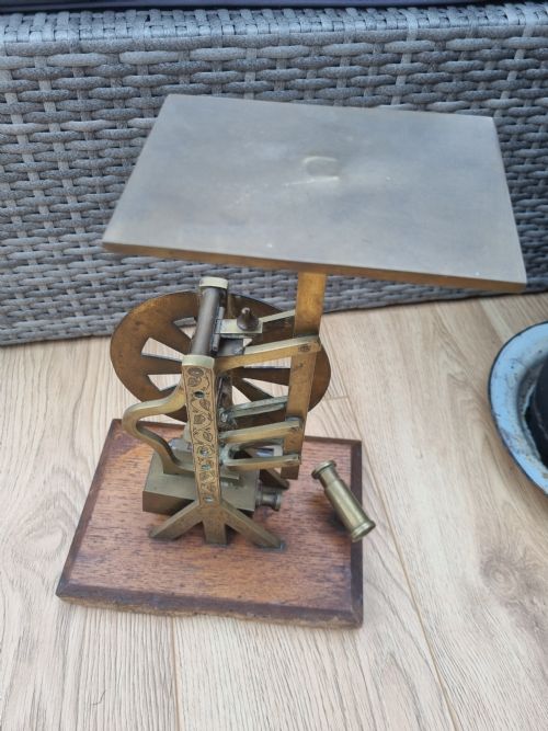 fig 1. An antique brass post office parcel scale with a circular dial indicator mounted on a rectangular wooden base.