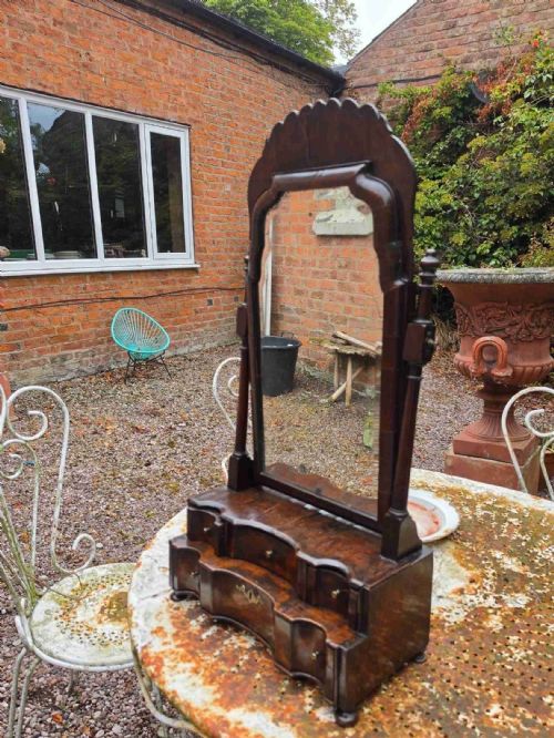 fig 1. An eighteenth-century George I patinated dark walnut toilet mirror featuring an arched adjustable swing glass over a two-tier serpentine drawer base with brass hardware.
