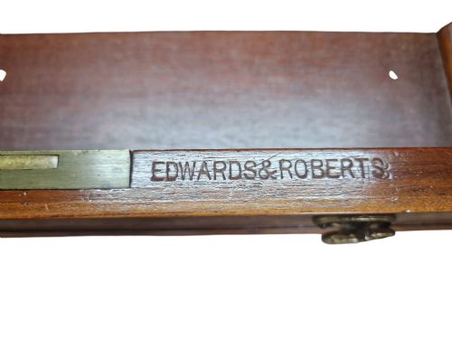 fig 1. An Edwardian mahogany writing desk featuring satinwood marquetry inlays, a dark leather writing surface, multiple drawers, and an upper glazed display cabinet topped with a broken-arch pediment.
