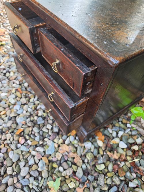 fig 1. An 18th-century dark oak chest featuring two short drawers over two long drawers with brass drop handles, resting on bracket feet.