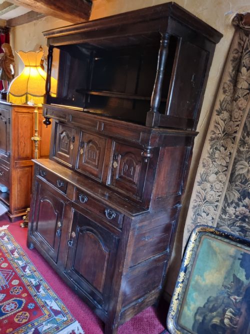 fig 2. An eighteenth-century dark oak Welsh tridarn featuring a three-tiered structure with carved arched panels, turned pillars, and an inscribed date.