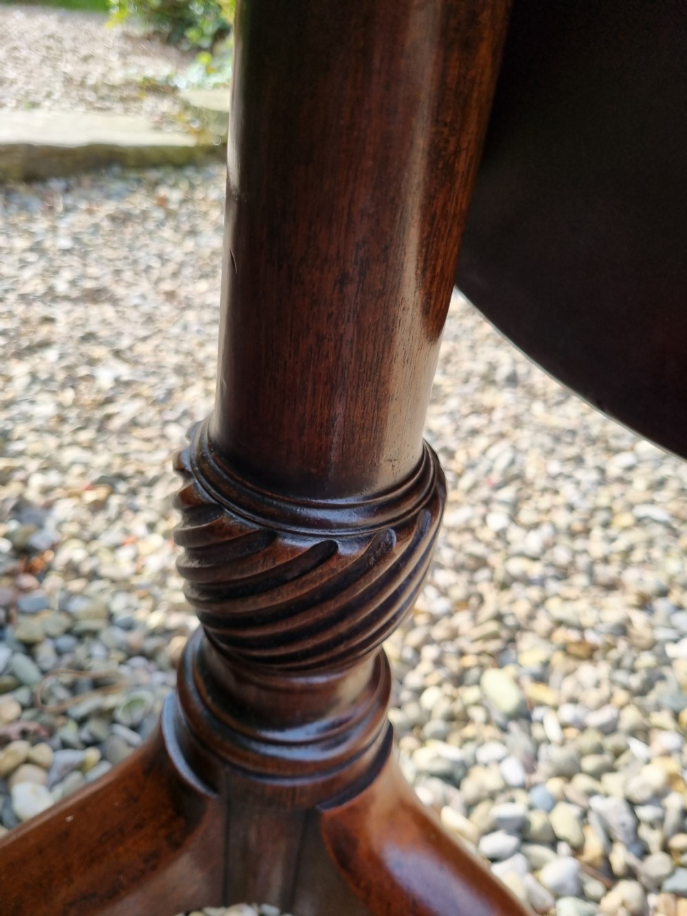 An antique Georgian circular mahogany tripod table shown tilted vertically on a turned stem with three cabriole legs. View III