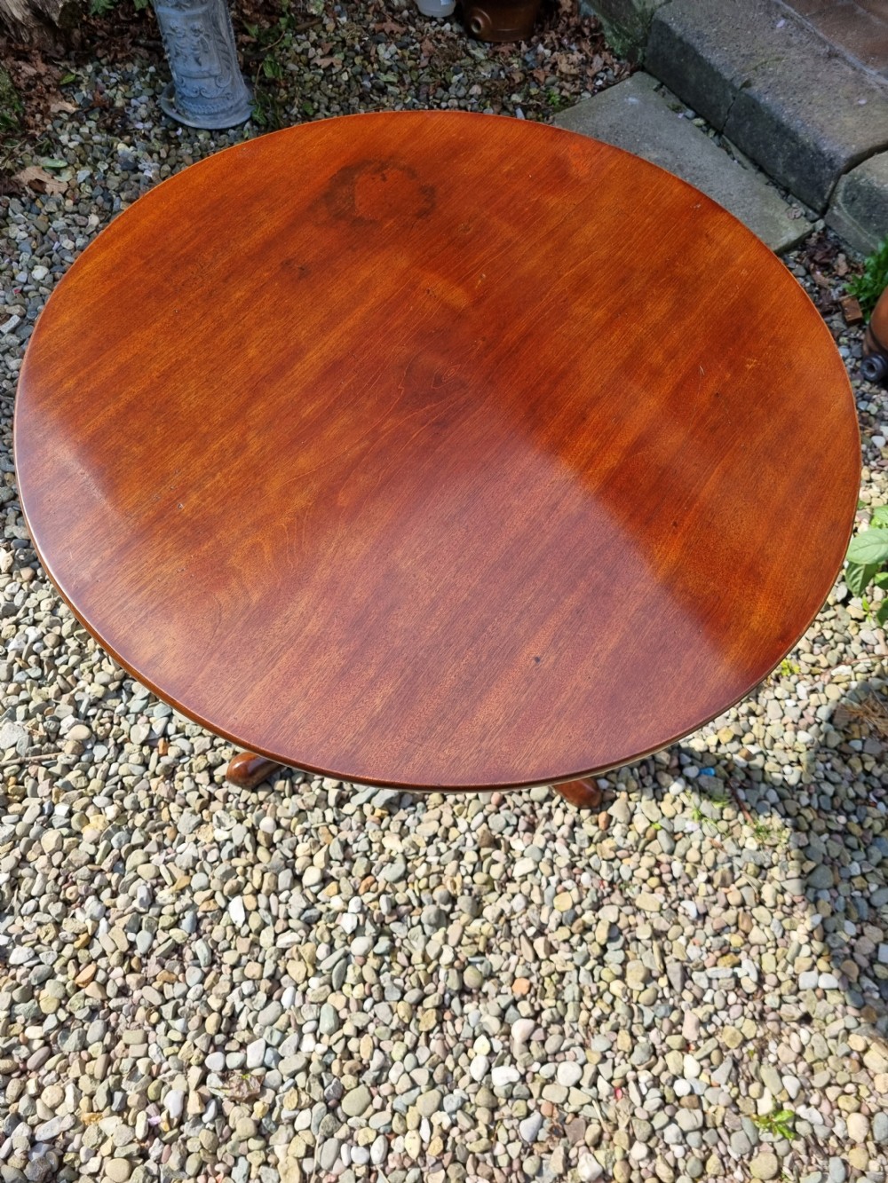 An antique Georgian circular mahogany tripod table shown tilted vertically on a turned stem with three cabriole legs. View VII