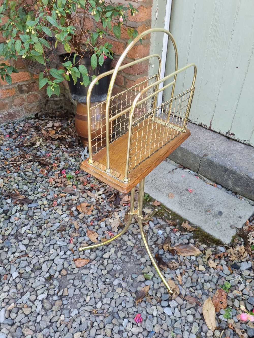 A tall standing brass magazine rack featuring a wire mesh basket, a polished mahogany base, and a three-legged brass tripod stand. View II
