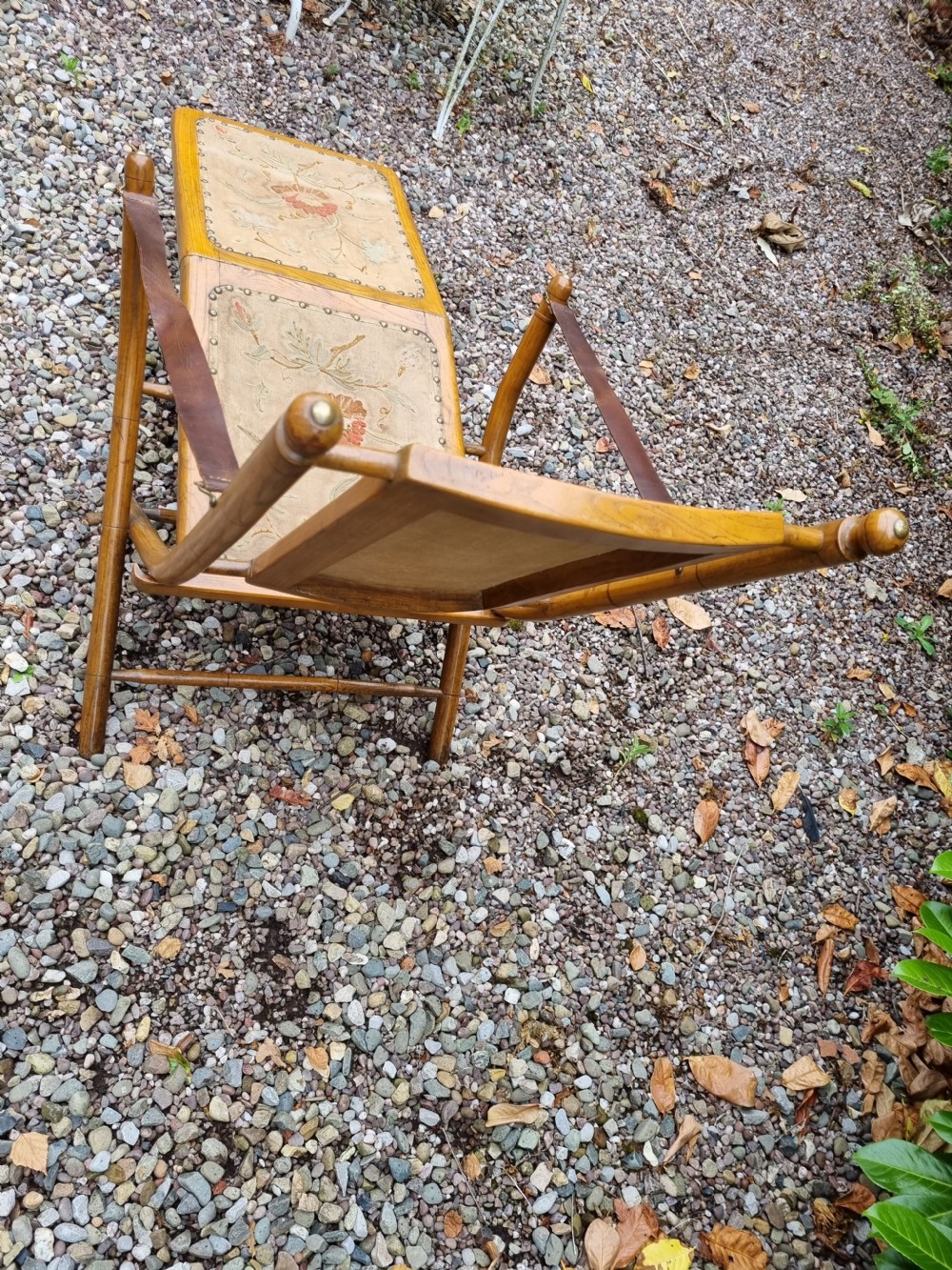 A 19th-century light oak folding lounge chair with floral tapestry panels, leather strap armrests, and an extended footrest. View V