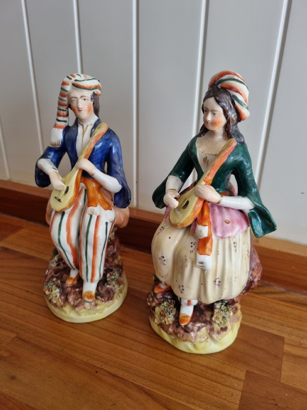 A pair of nineteenth-century Staffordshire earthenware figures depicting a seated male and female musician in colourful orientalist costume playing lutes.