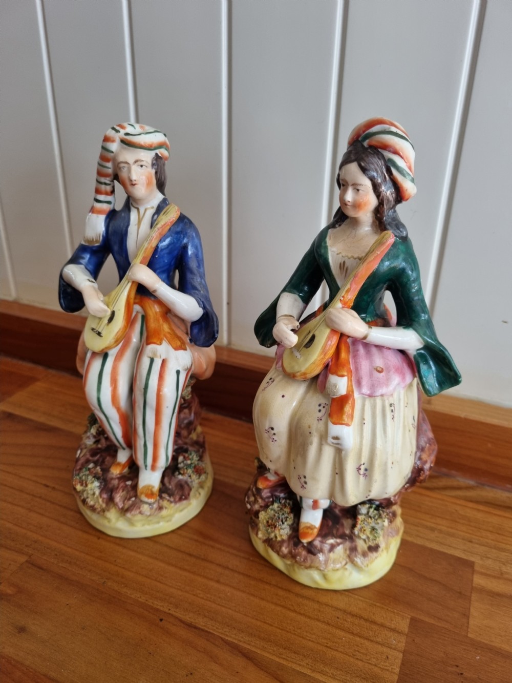A pair of nineteenth-century Staffordshire earthenware figures depicting a seated male and female musician in colourful orientalist costume playing lutes. View VI