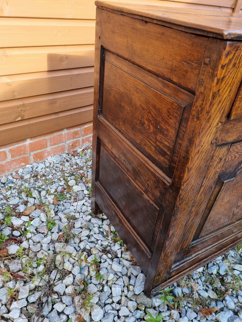 A mid-18th century dark oak dresser base featuring three top drawers over three fielded panel cupboard doors with brass swan neck handles. View III