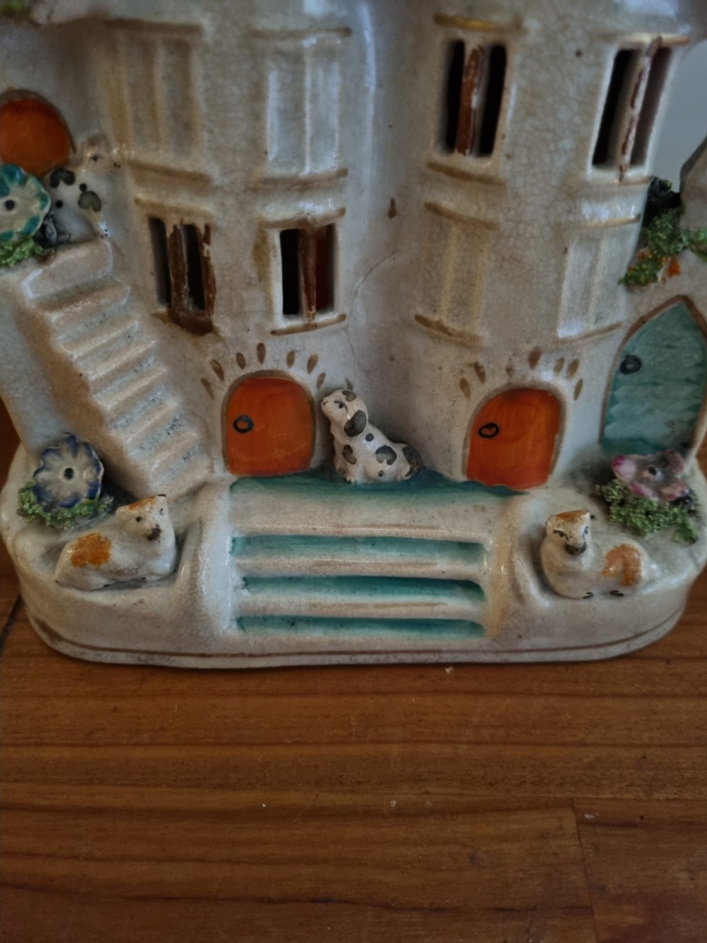 A 19th-century Staffordshire earthenware pastille burner styled as a cream twin-gabled mansion with applied green foliage and painted red doors. View II