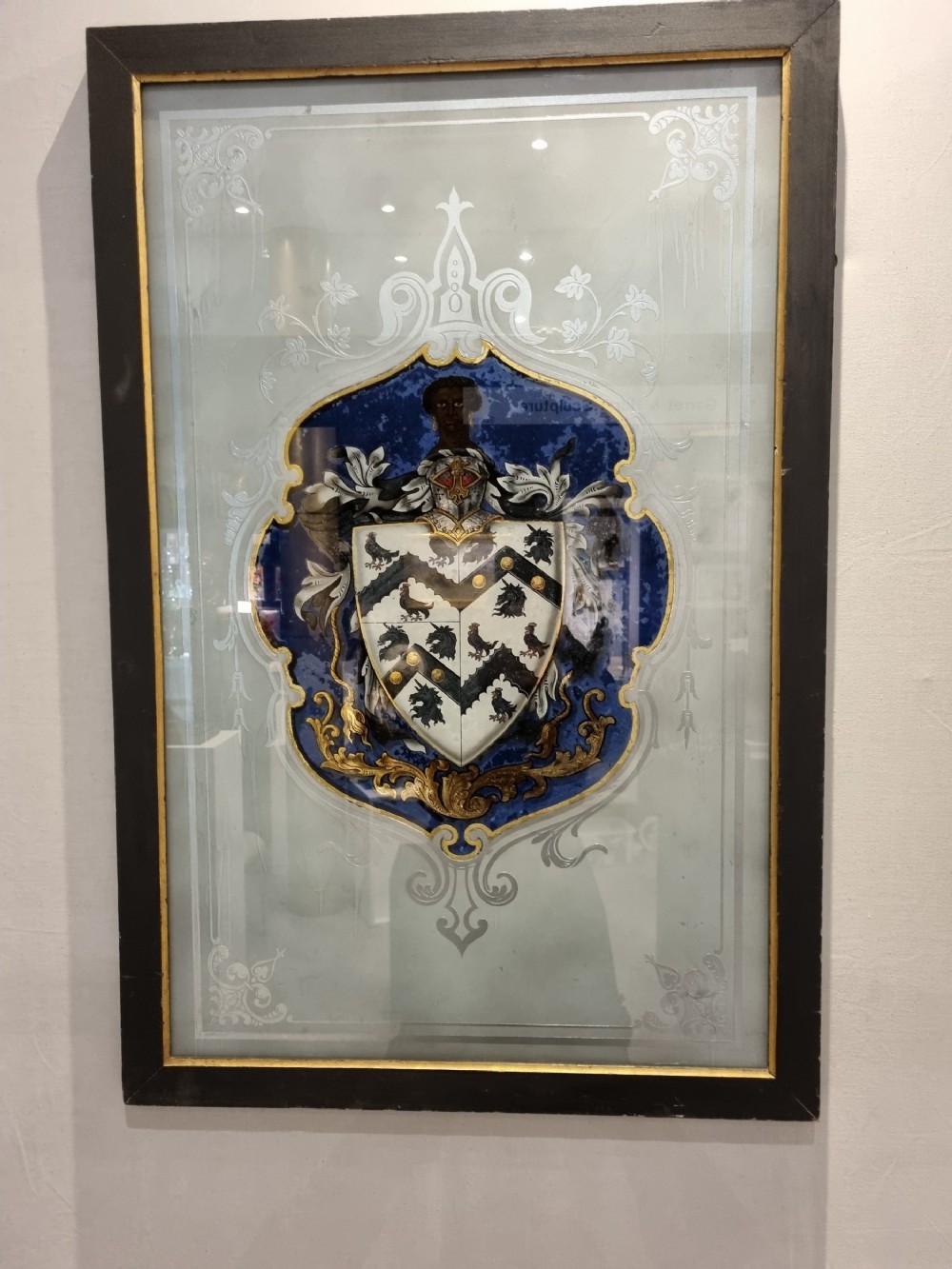 A VERRE EGOMISE GLASS  FRAMED PANEL.BEARING THE ARMS OF ST THOMAS MORE 