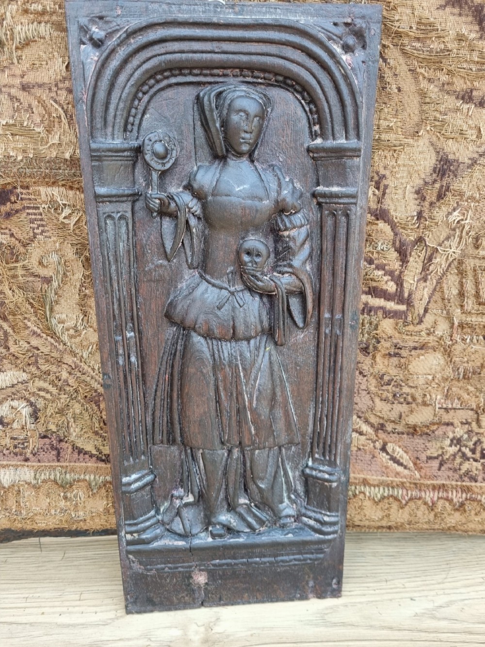 E 17THC OAK CARVED PANEL OF A LADY HOLDING A SKULL AND ORB.