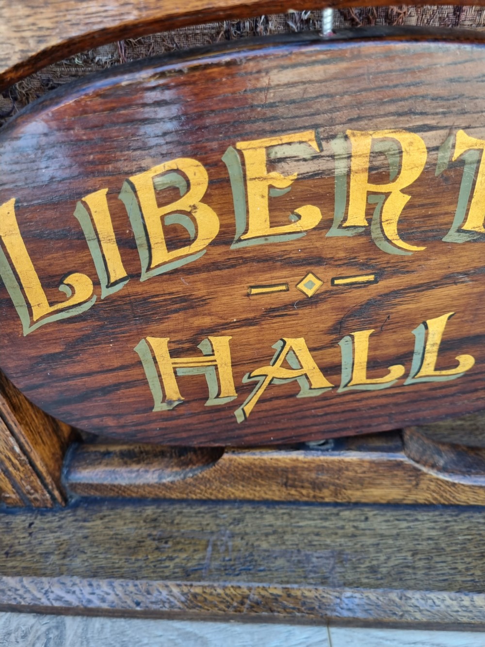 A pair of carved dark oak tabletop signs with oval central plaques featuring painted gold lettering reading Liberty Hall and Strict Order. View IV