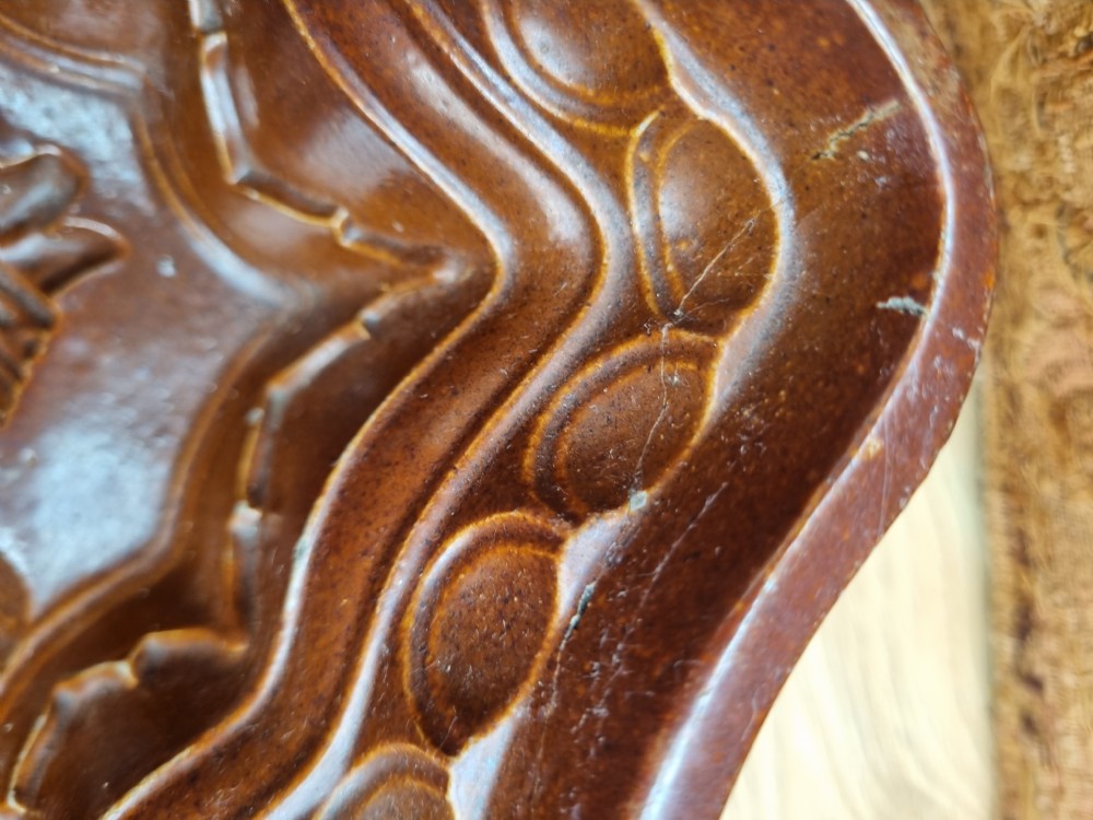 A square brown glazed stoneware jelly mould with a central Prince of Wales feathers relief motif and stepped fluted sides. View V