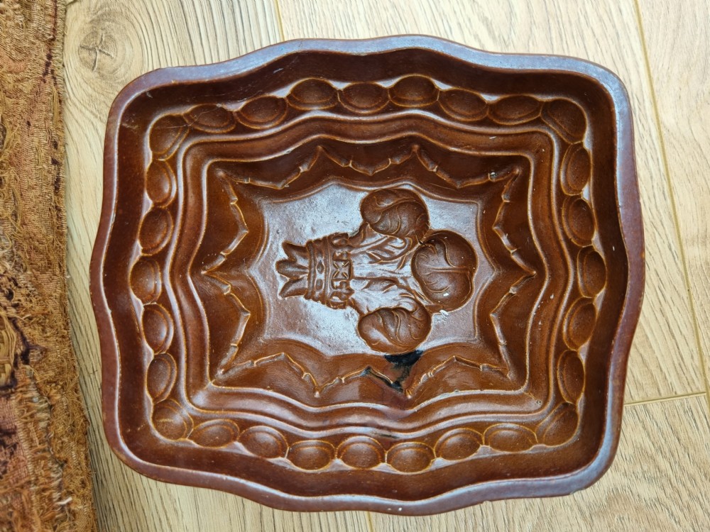 A square brown glazed stoneware jelly mould with a central Prince of Wales feathers relief motif and stepped fluted sides. View VI