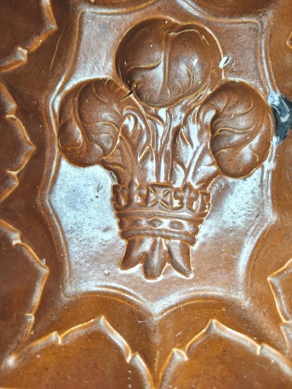 A square brown glazed stoneware jelly mould with a central Prince of Wales feathers relief motif and stepped fluted sides. View VII