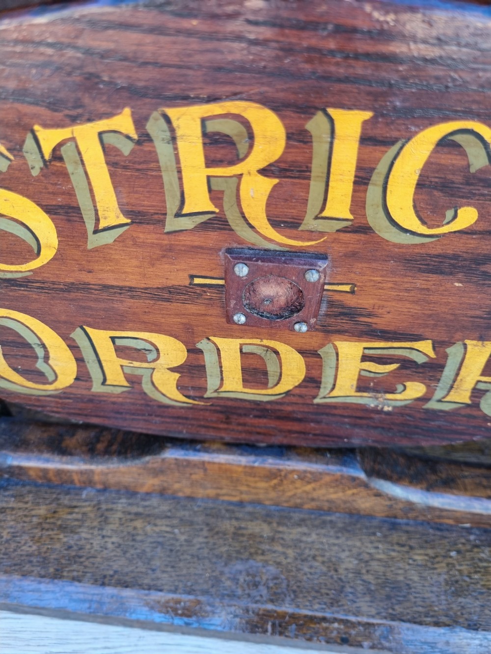 A pair of carved dark oak tabletop signs with oval central plaques featuring painted gold lettering reading Liberty Hall and Strict Order. View VI