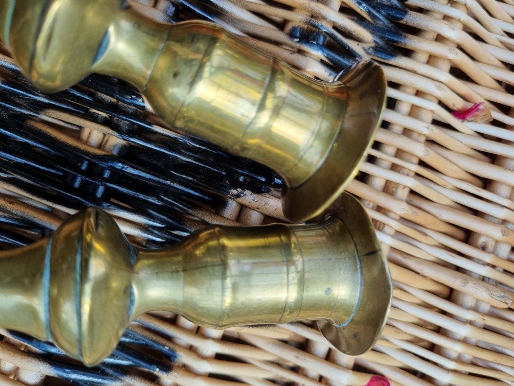 A pair of 18th-century Georgian bell metal candlesticks with turned baluster stems and shaped petal bases. View V