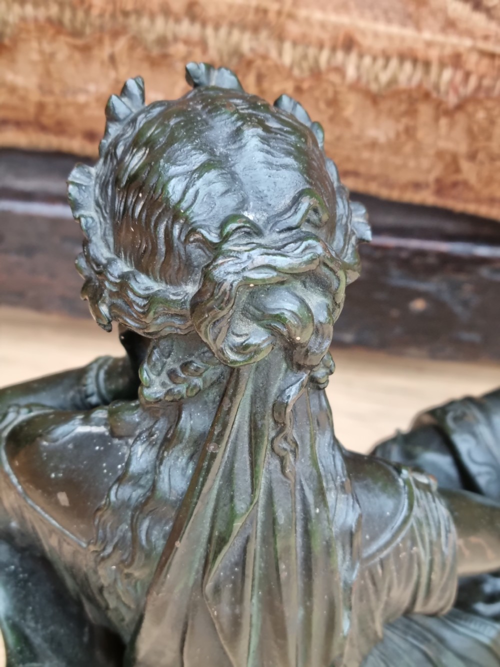 A 19th-century dark green patinated bronze figure depicting a seated classical woman in draped clothing resting her chin on her hand. View IV