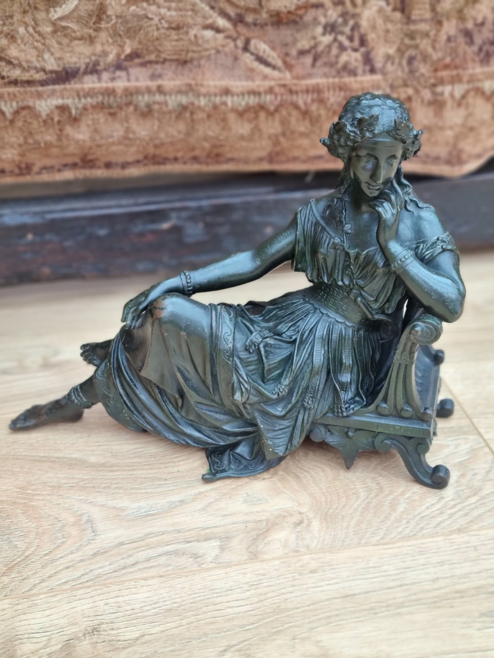 A 19th-century dark green patinated bronze figure depicting a seated classical woman in draped clothing resting her chin on her hand. View VI