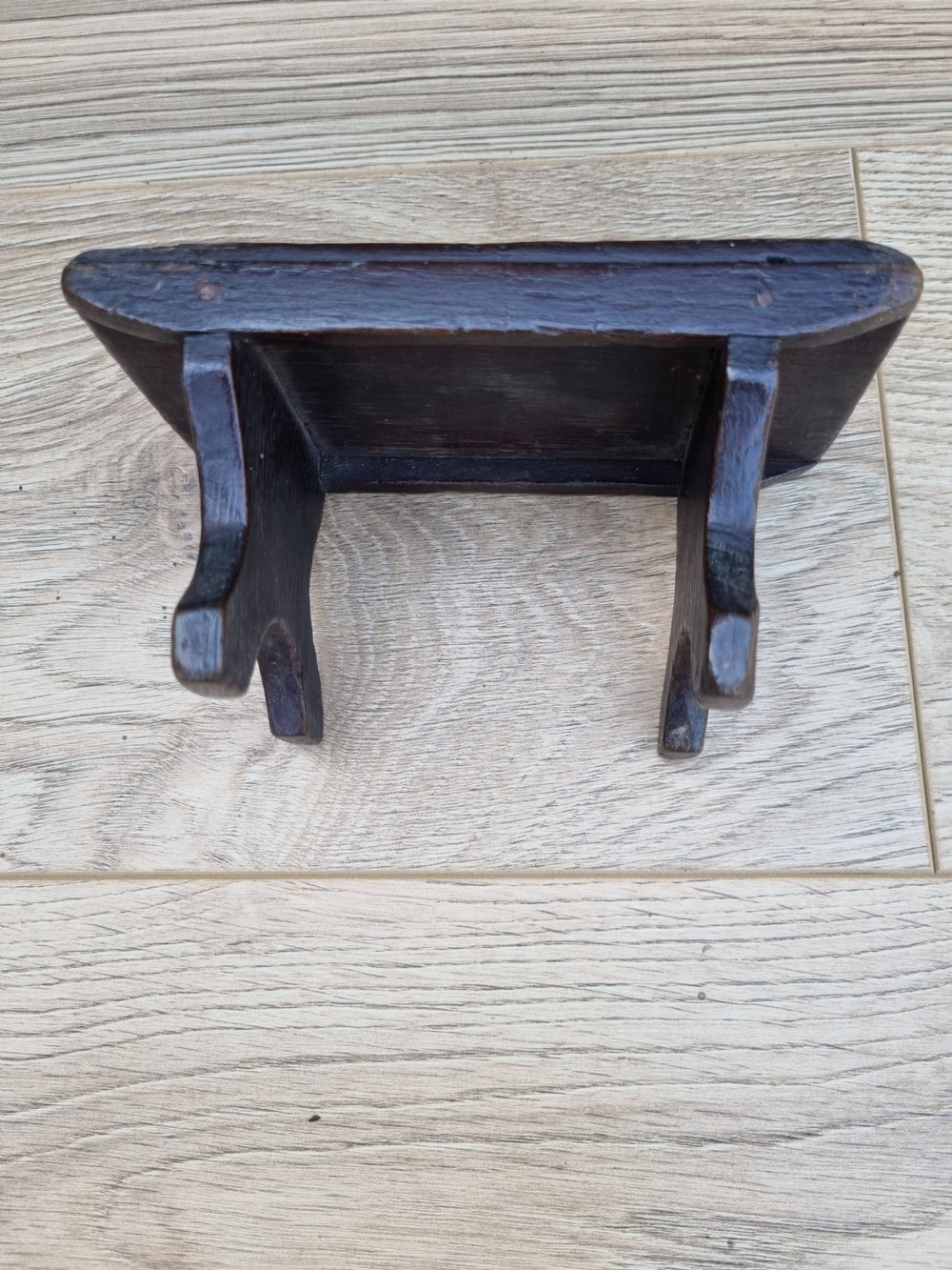A 19th-century dark elm miniature Welsh stool with a solid rectangular top and carved arch side supports showing age-related wear. View III
