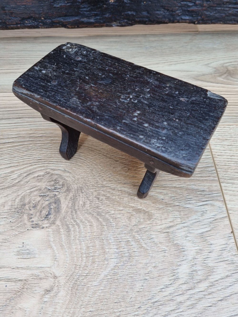 A 19th-century dark elm miniature Welsh stool with a solid rectangular top and carved arch side supports showing age-related wear. View V