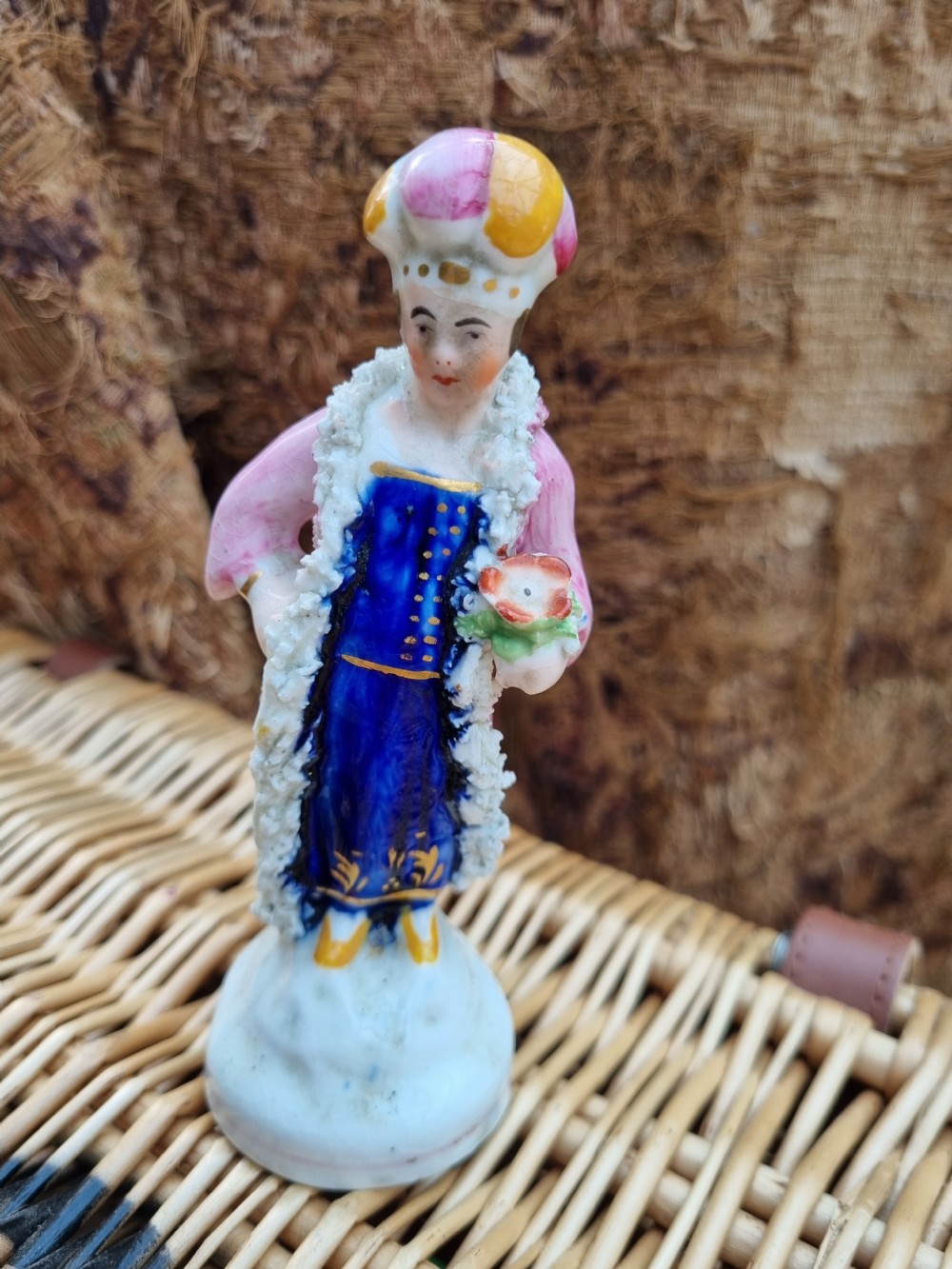 A 19th-century Staffordshire earthenware ceramic figurine depicting a figure wearing a turban, pink coat, and cobalt blue tunic with white textured trim. View VI