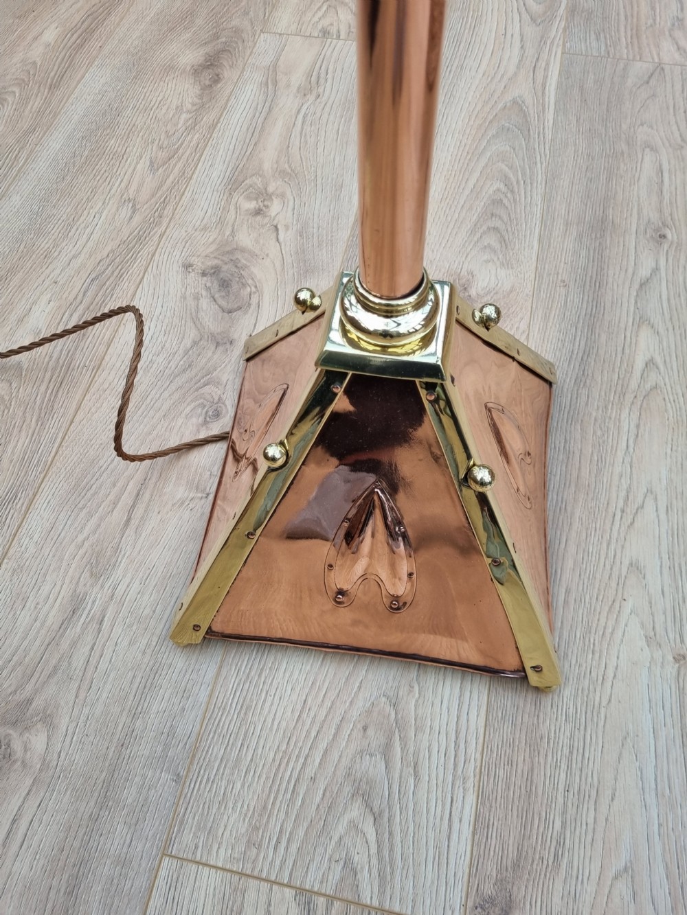 An Arts and Crafts style standard lamp crafted from copper and brass featuring a pyramidal base with decorative relief motifs and an extended central column. View II