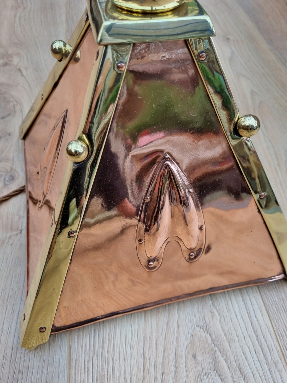 An Arts and Crafts style standard lamp crafted from copper and brass featuring a pyramidal base with decorative relief motifs and an extended central column. View V