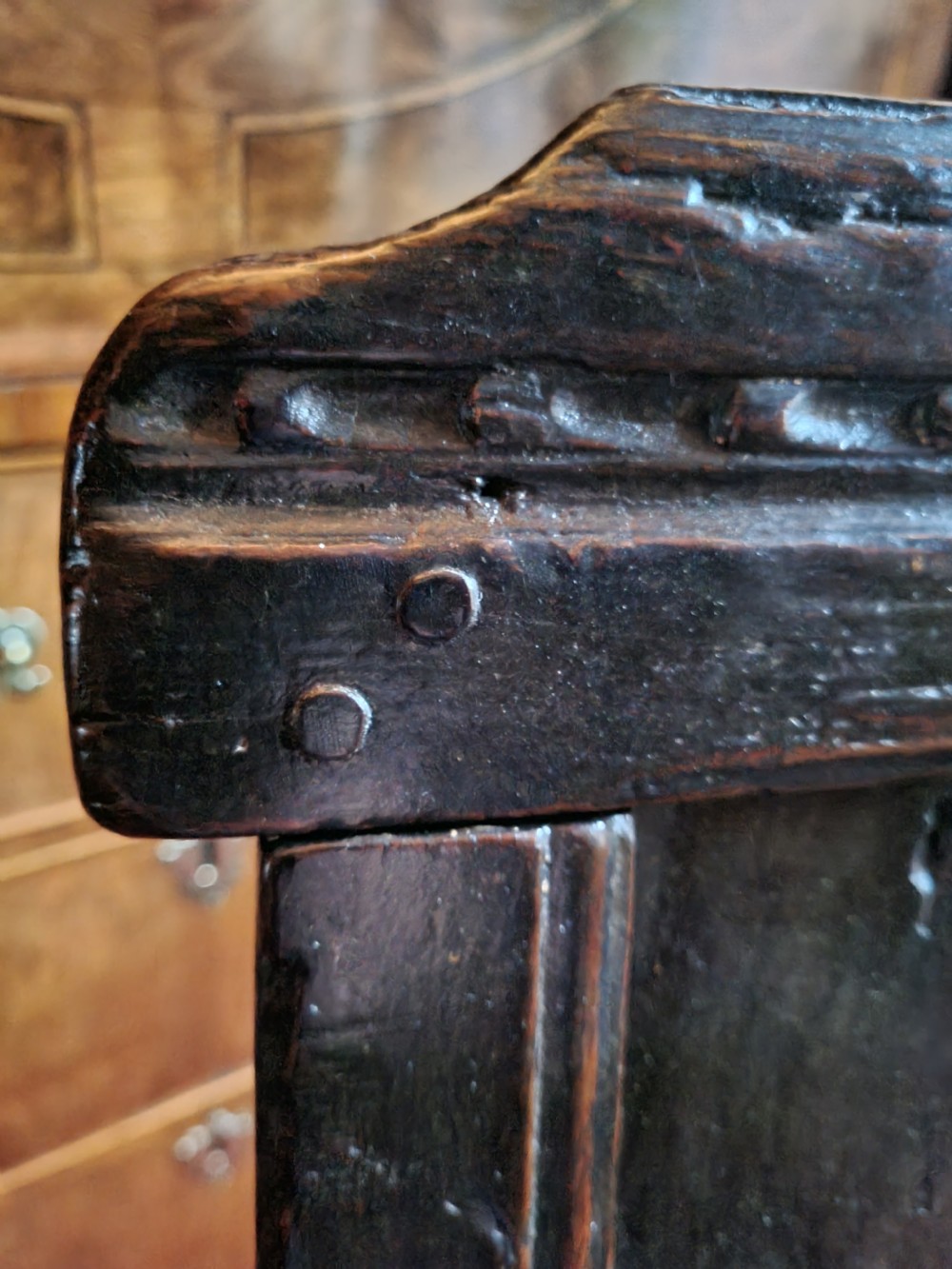 A seventeenth-century dark oak wainscot armchair featuring a solid panelled backrest, carved top rail, curved armrests, and turned leg supports. View VIII