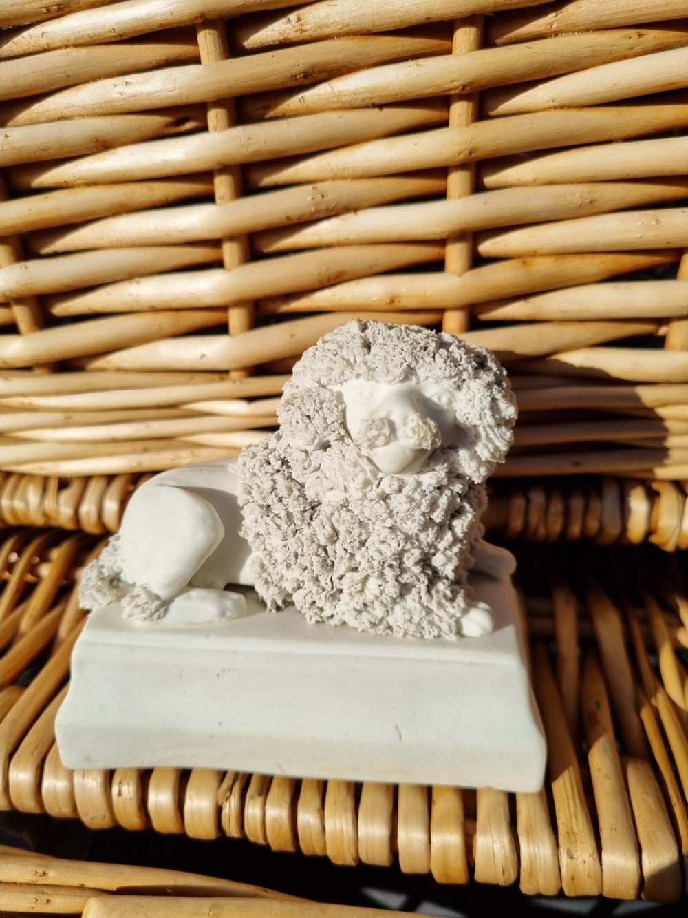 An early 19th-century off-white bisque porcelain figurine of a recumbent poodle with texturized ceramic fur resting on a rectangular stepped base. View IV