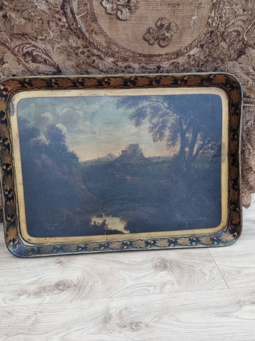 An 18th-century rectangular papier-mache tray featuring a painted landscape scene with figures fishing and a gilded foliate border. View VIII