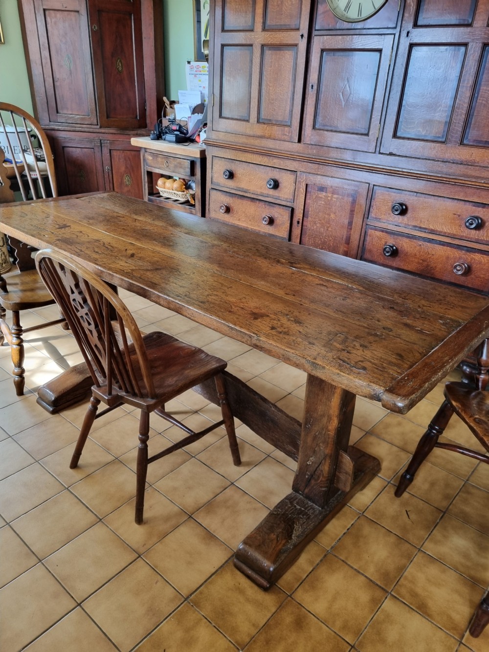 An antique dark oak refectory dining table featuring a plank top supported by a sturdy trestle base. View II