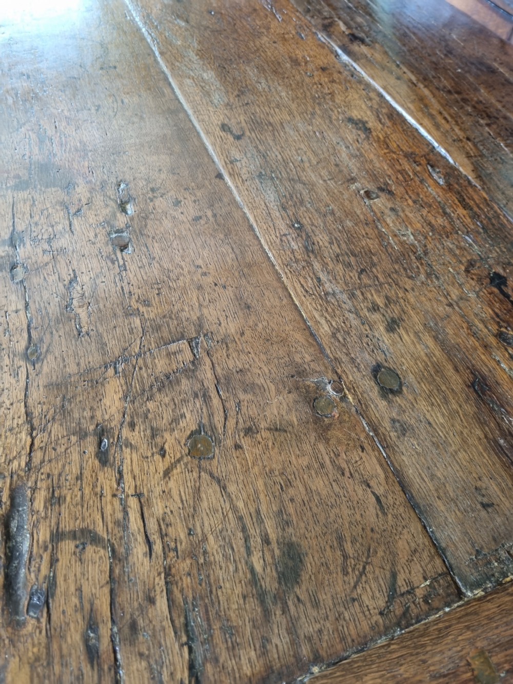 An antique dark oak refectory dining table featuring a plank top supported by a sturdy trestle base. View III